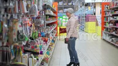 一个戴着帽子和羽绒服的女人穿过超市。 她从货架上拿货，选择购买